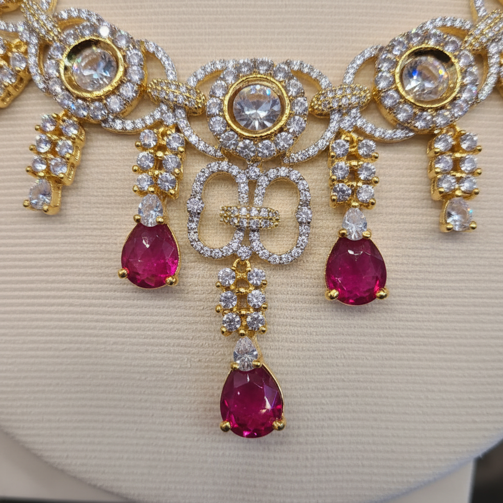Close-up of a gold-tone crystal-style floral cluster with a faceted ruby-colored teardrop drop