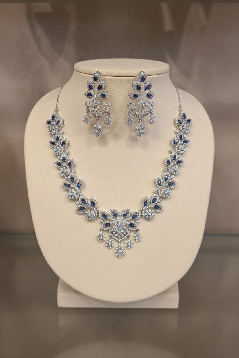 Silver-tone necklace set with blue stones and matching drop earrings on an ivory jewelry bust