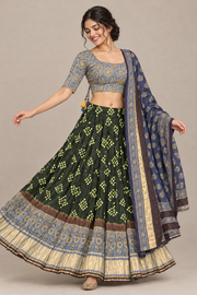 Female model in front three-quarter view wearing green patterned lehenga, floral blouse and navy dupatta