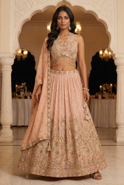 Front view of blush peach embellished lehenga with sleeveless blouse and matching dupatta, styled with soft waves.