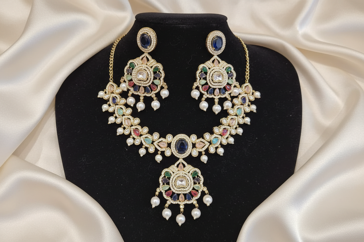 Gold-tone necklace and matching earrings arranged on black velvet with pearl-like drops and multicolor accents.