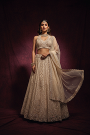 Ivory sequin bridal lehenga – front facing pose, dark maroon background