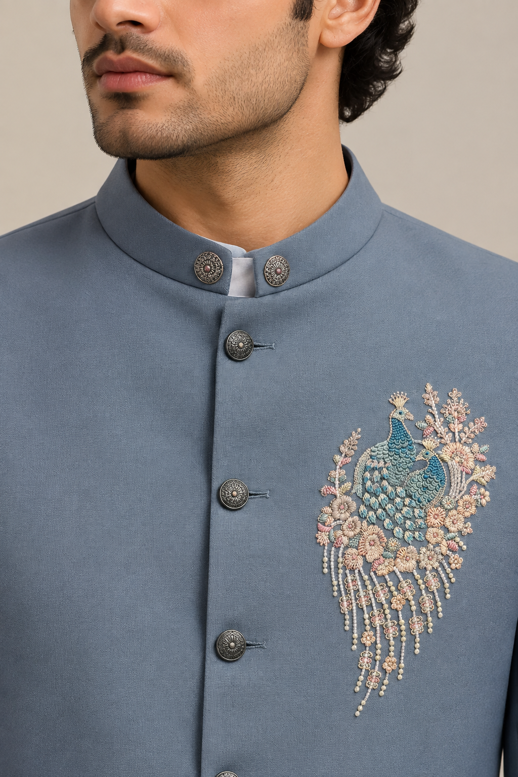 Close-up of slate-blue jacket standing collar, buttons, and bird-and-floral chest motif
