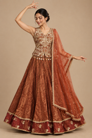 Front view of rust floral lehenga set on a female model in a Garba-inspired pose