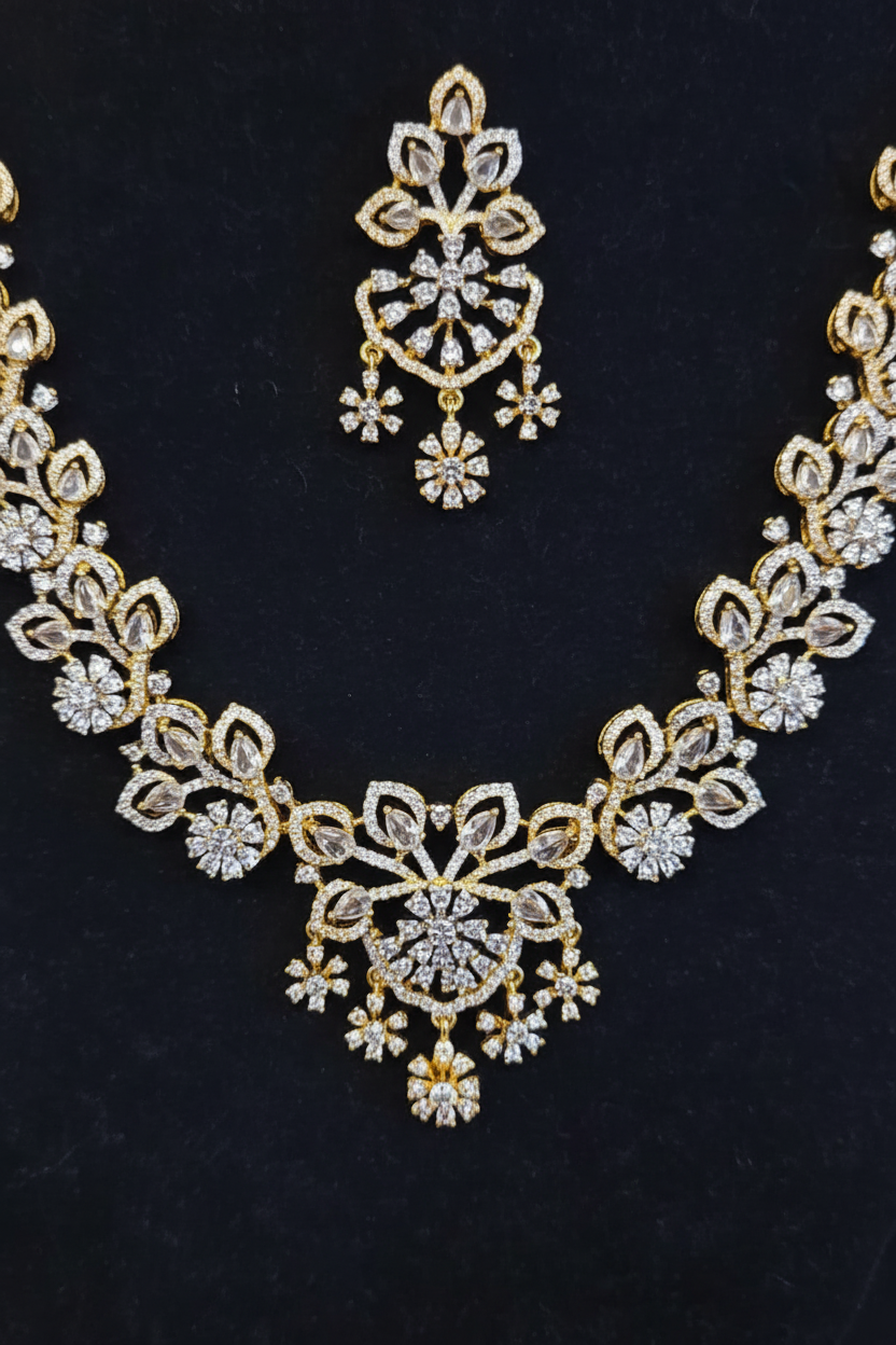 Close-up of the gold-tone floral crystal center pendant and matching chandelier earring from the Trisha Necklace Set on dark blue