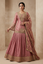 Front view of a female model in a dusty rose lehenga with a long gold-embellished blouse, flared sleeve cuffs and matching dupatta