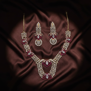 Flat lay of the Shreya gold-tone necklace and matching chandelier earrings on dark silk