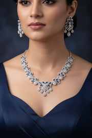 Model wearing a silver-tone blue stone necklace set with cascading pendant and matching earrings