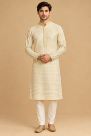 Front view of model in ivory gold-patterned kurta with off-white trousers and tan slip-on shoes