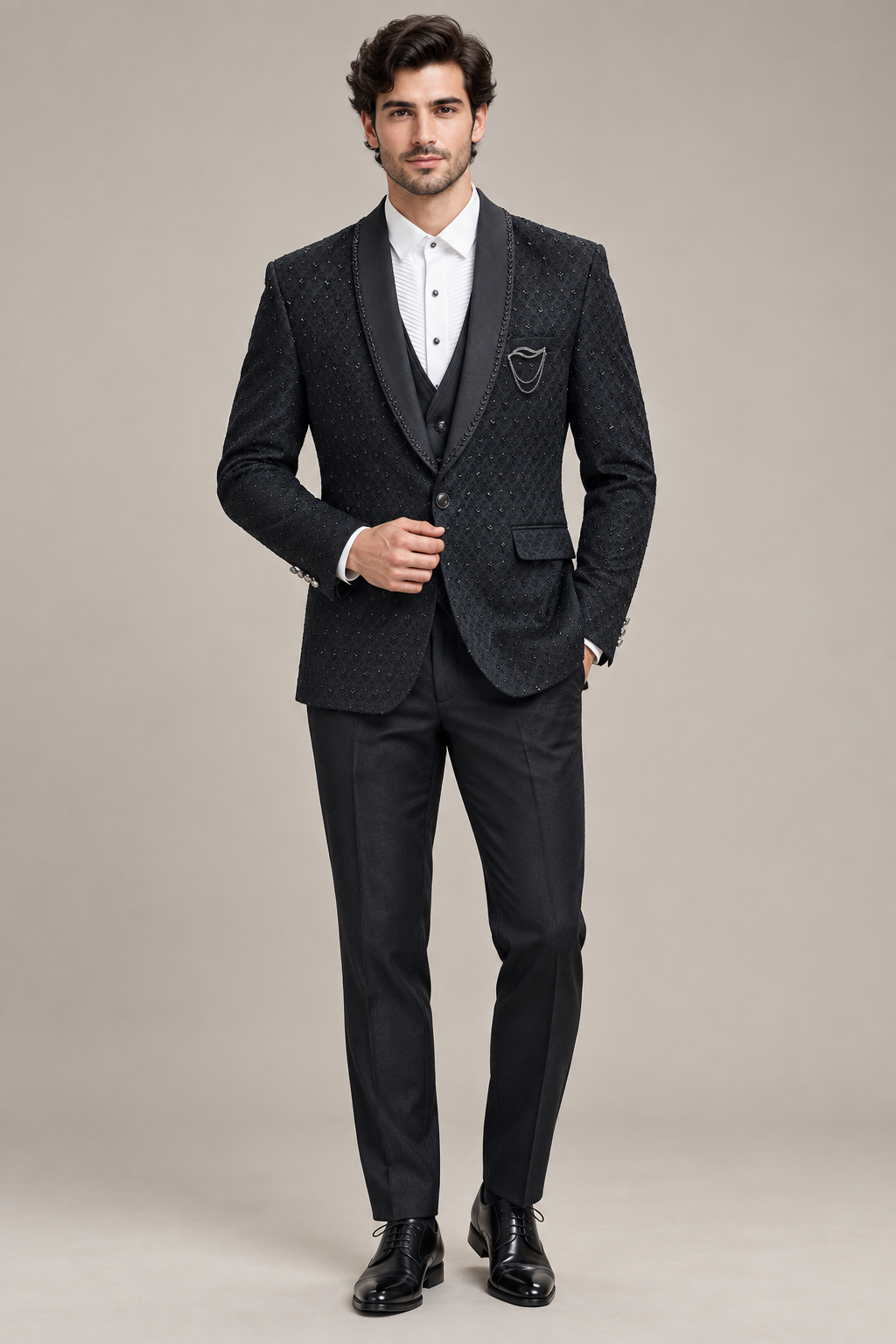 Front view of model in dark patterned jacket, waistcoat and white pleated-front shirt with black dress shoes