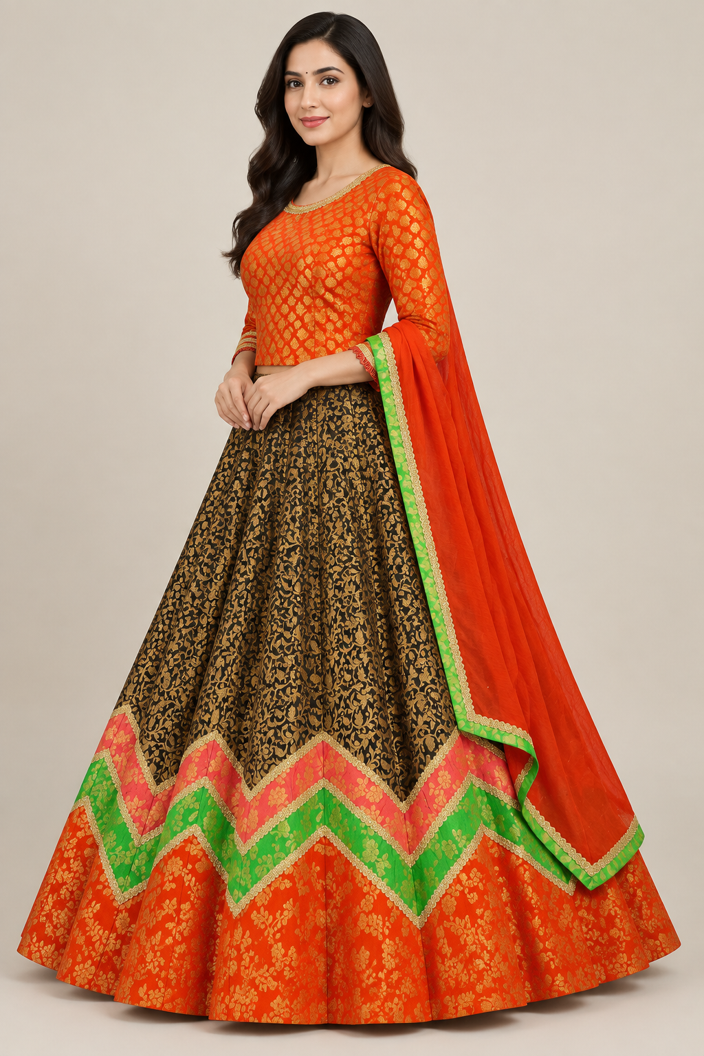 Angled model view in waist-length orange blouse and dark patterned lehenga