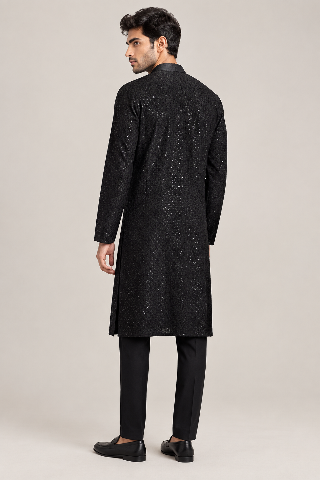 Rear three-quarter view of black shimmer kurta on male model with black trousers and loafers