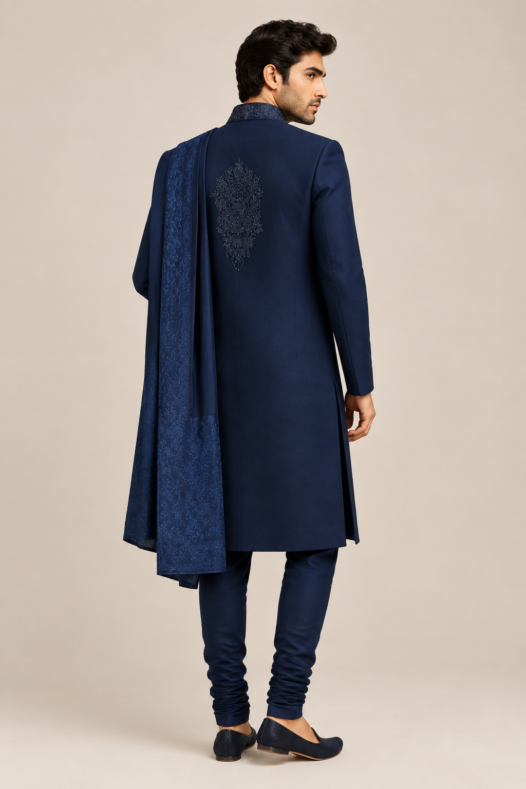 Rear three-quarter view of model wearing navy beaded-collar sherwani set with matching churidar and dupatta