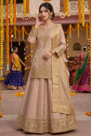 Front view of champagne gold lehenga on a model with soft updo in a festive Garba courtyard