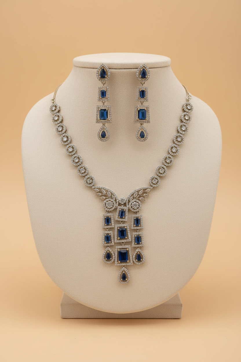 Silver-tone blue stone necklace set with matching earrings on an ivory velvet bust