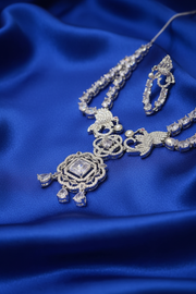 Angled close-up of the Shristi necklace pendant and earring on royal blue silk