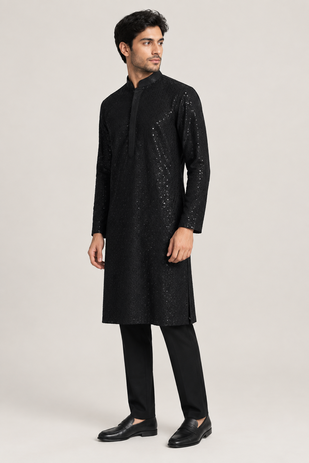 Male model wearing black shimmer kurta with black trousers and loafers, side view