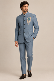 Male model in slate-blue bird-motif band-collar jacket and matching trousers, front three-quarter view
