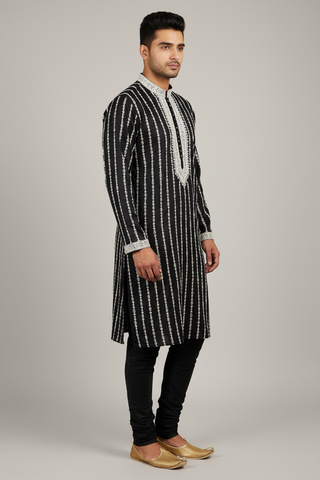 Male model wearing black embroidered kurta set with gold juttis - side profile