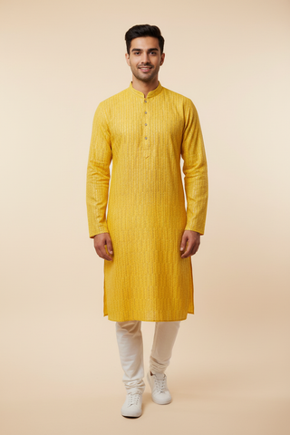 Male model wearing yellow chikankari kurta set with white sneakers - front pose
