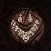 Flat lay of the Jennifer gold-tone necklace and matching earrings on dark silk
