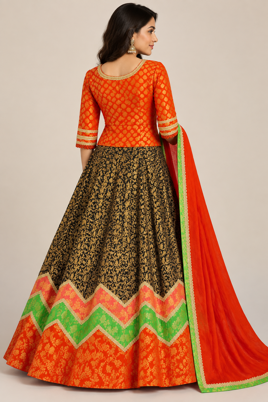 Rear model view in waist-length orange blouse and dark patterned lehenga